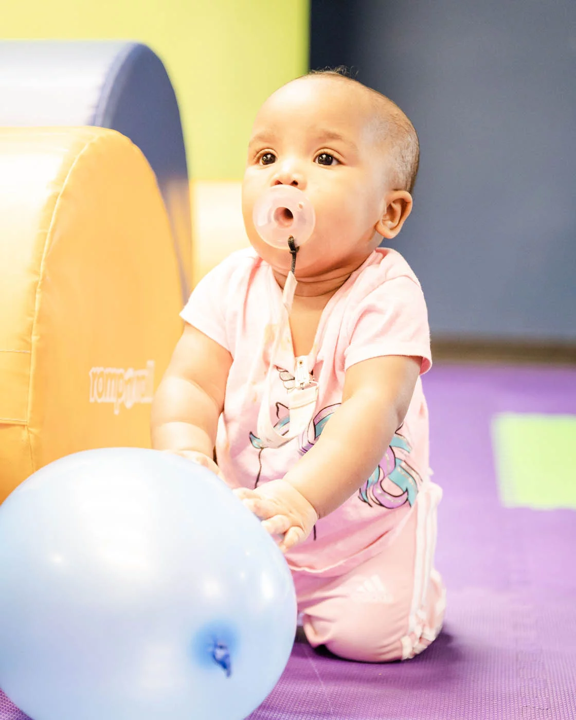 A young baby boy playing with a balloon at Romp n' Roll.