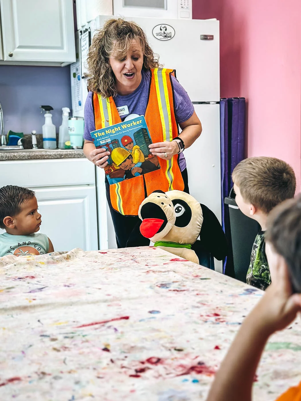 A Romp n' Roll instructor reading a book to Rompy and a room full of children at a child entertainment franchise class.