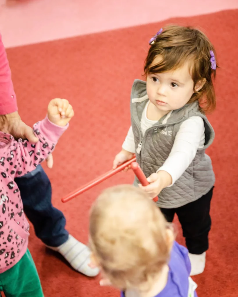 A little girl playing with music instruments at Romp n' Roll's kids night out event.