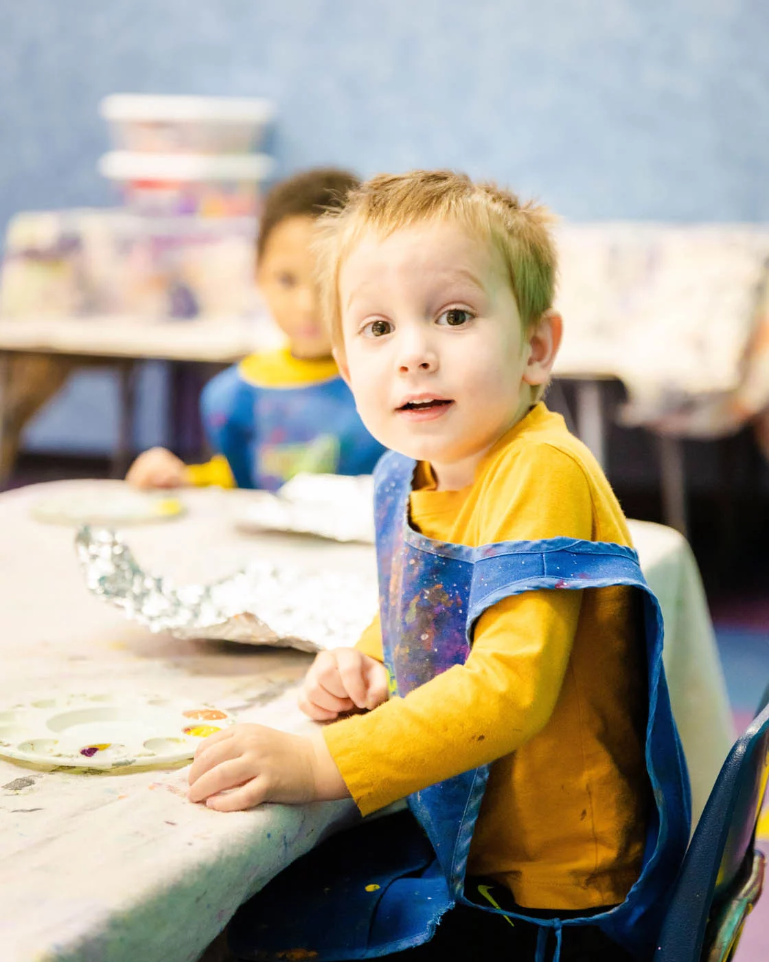 A little boy sitting at an art table.