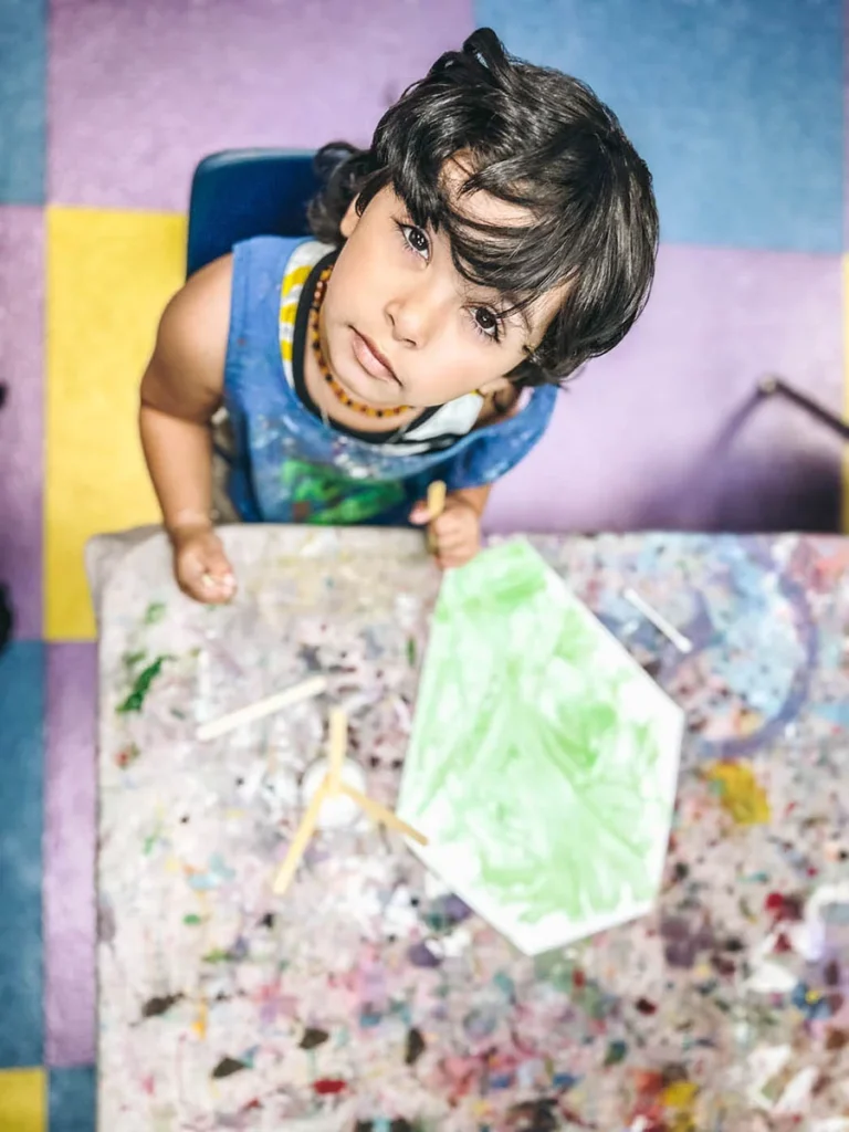 Romp n' Roll little boy looking up at the camera during an art class.