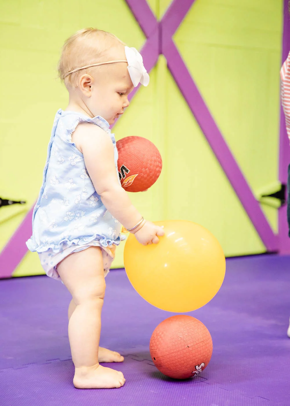 A baby playing with balloon and balls at Romp n' Roll.