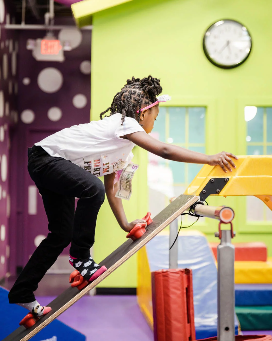 A young girl climbing up to slide down a yellow slide at Romp n' Roll - a unique kids fitness franchise!