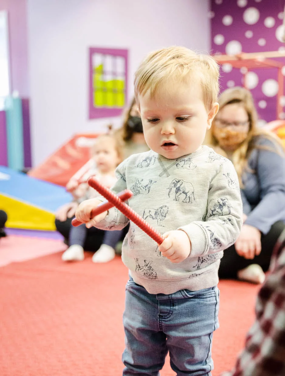 A kid playing with musical instruments at Romp n' Roll - a kids gym franchise.